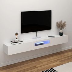 a flat screen tv sitting on top of a white entertainment center next to a plant