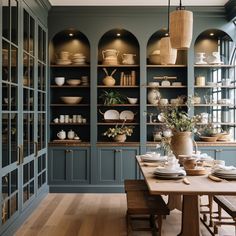 a dining room table with plates and bowls on it, surrounded by built - in shelving