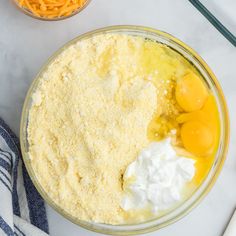 the ingredients to make this cake are in bowls on the counter top, including eggs and cheese