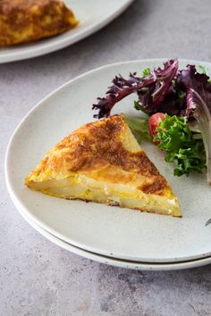 there is a slice of quiche and salad on the plate