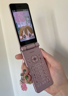 a person holding up a cell phone with an anime character on the screen and keychain attached to it