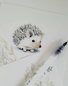 a drawing of a hedgehog sitting on top of a piece of paper next to a pen