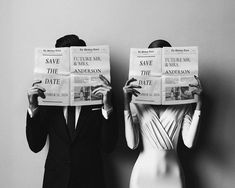 two people in suits are holding newspapers over their heads as they stand next to each other