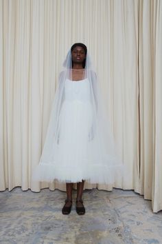 a woman standing in front of a curtain wearing a veil