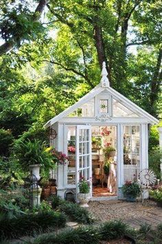 a small white house surrounded by trees and flowers