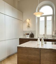 a large kitchen with white cabinets and marble counter tops, along with an arched window