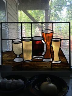 a stained glass window with beer glasses and pumpkins on the table next to it