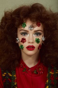 a woman with christmas decorations on her face and red lipstick is shown in front of the camera