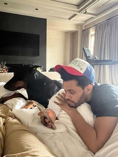 a man laying on top of a bed next to a black and brown dog in a living room