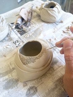 a person is making something out of clay on a table with newspaper and other items