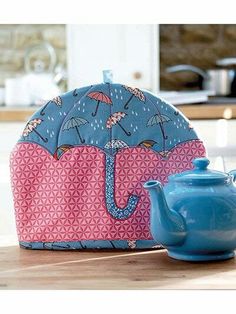 a blue tea pot sitting on top of a wooden table next to an umbrella bag