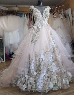 a dress made out of flowers on display in a room with other wedding gowns