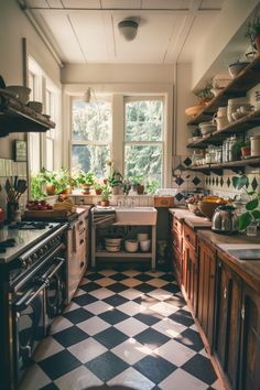 a kitchen with black and white checkered flooring next to a window filled with potted plants