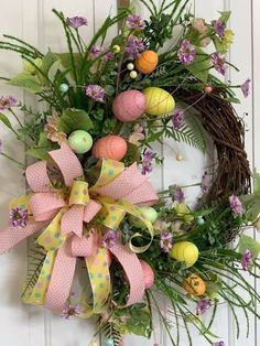 an easter wreath with eggs and flowers on the front door, hanging from a wall