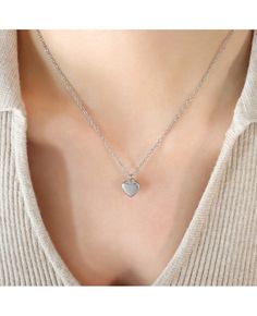 a woman wearing a necklace with a heart pendant on the back of her neck,