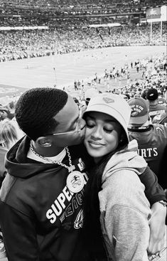 a man and woman kissing in front of a crowd at a baseball game with fans