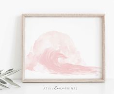 a pink and white painting in a wooden frame on a shelf next to a plant