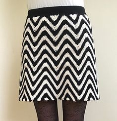 a woman wearing black and white patterned skirt with tights on her legs, standing in front of a wall