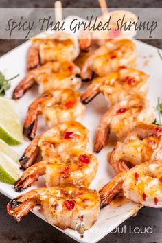 grilled shrimp on a white plate with lime wedges