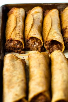 several burritos sitting in a pan on top of a table