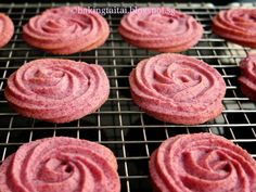 pink cookies cooling on a wire rack with red powdered sugar in the middle,