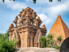 an old stone structure in the middle of some trees and bushes with two pyramids behind it