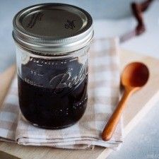 a wooden spoon sitting on top of a table next to a jar filled with black liquid