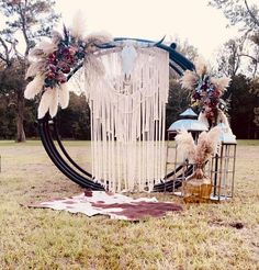 an outdoor ceremony setup with feathers, flowers and other things on the ground in front of it