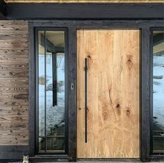 a cat sitting on the ground in front of a wooden door with glass and black trim