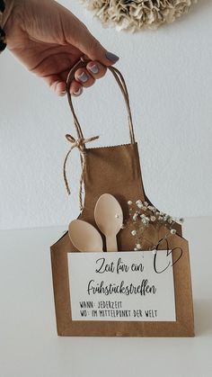 a person holding a brown paper bag with wooden spoons in it and a tag attached to the handle