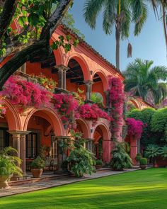 an orange building with pink flowers on the outside and green grass in front of it