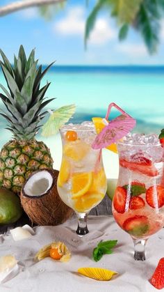 three glasses filled with different types of drinks on top of a table next to the ocean