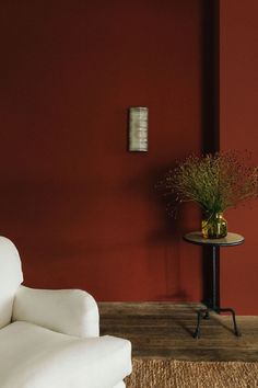 a chair and table in a room with red paint on the walls, and a white couch