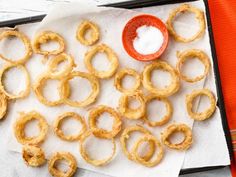 some onion rings are sitting on a towel next to a small bowl with salt in it