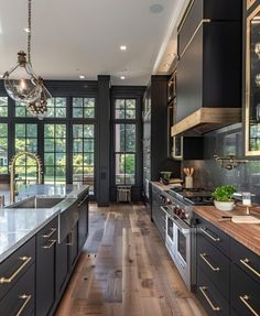 a large kitchen with black cabinets and wood flooring is pictured in this image from the front view