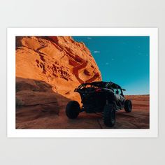 a four - wheeled vehicle is parked in front of a large rock formation on a sunny day