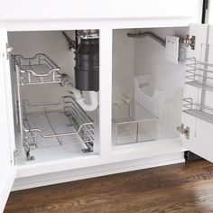 an open kitchen cabinet with metal shelves and wire baskets on the bottom, in front of a wood floor