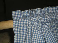 a blue and white checkered curtain hanging from a wooden rod with a baseball bat in the background