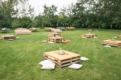 several wooden pallets sitting in the middle of a grassy field with pillows on them