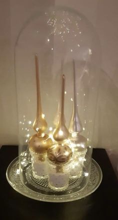 three desserts under a glass dome with lights on it's sides and spoons in the middle