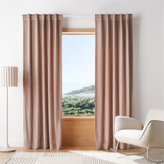 a living room with a white chair and large window covered in pink drapes that are open to the outside