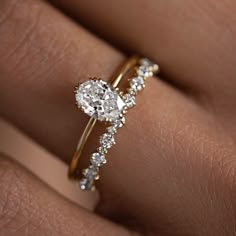 a woman's hand with a diamond ring on top of her finger and an engagement band