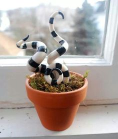 a fake snake sitting on top of a potted plant in front of a window