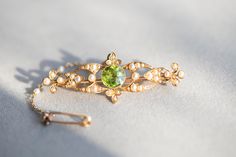 Edwardian peridot and seed pearl bar brooch. VIDEO https://youtu.be/2dqmfwkwrfE https://youtu.be/LcAQcLa-tuE DETAILS 15 carat yellow gold. Brooch width 5cm, length 2cm, weight 5.2g. CONDITION REPORT Pre-owned. Great vintage condition. Refer to pictures & videos. HALLMARKS: tbc LIKE IT? Make a perfect vintage GIFT!  All our jewellery comes beautifully packed in one of the Kashovska Vintage Collection original boxes. However if you would like to pair your vintage pendant with an authentic antique Antique Green Gemstone Brooches, Green Gemstone Wedding Brooches, Antique Green Brooches For Wedding, Vintage Gold Peridot Jewelry, Vintage Gold Jewelry With Peridot, Bar Brooch, Jewellery Vintage, Antique Green, Gold Brooch