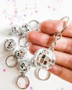 a person is holding several disco ball key chains