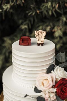 a wedding cake decorated with flowers and two small figurines sitting on top of it