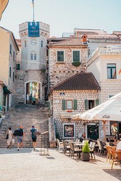 people are walking up and down the stairs in an old town with stone buildings on either side