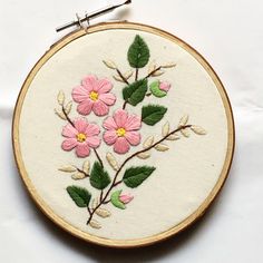 a close up of a embroidery on a piece of cloth with flowers and leaves in it