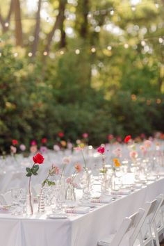 a long table is set up with white linens and flowers in glass vases