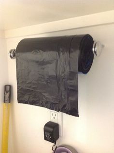 a roll of toilet paper is hanging on the wall next to a trash bag holder